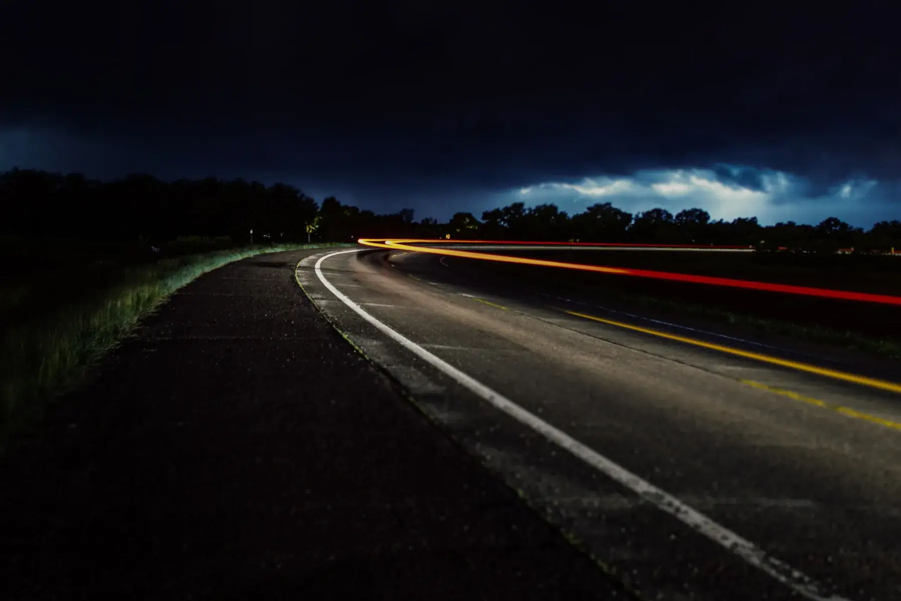 A country road at night, with light trails from passing cars